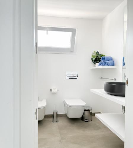 a white bathroom with a toilet and a sink at Island Home Fuerteventura in Corralejo