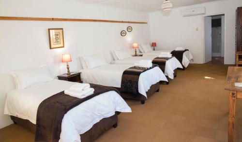 a group of four beds in a hotel room at Roode Bloem Farm House in Graaff-Reinet