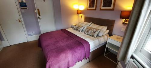 a bedroom with a large bed with a purple blanket at Colebrook Guest House in Farnborough
