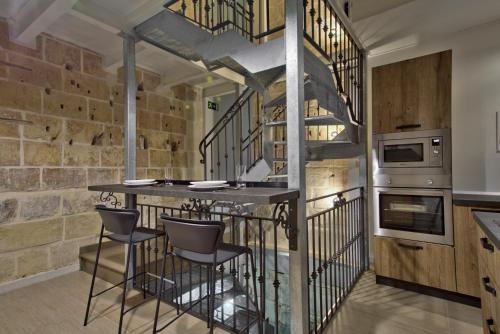 a kitchen with a bar and a spiral staircase at Chateau La Vallette - Grand Master's Suite in Valletta