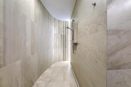 a bathroom with a walk in shower next to a wall at Aparthotel New Lux in Wrocław