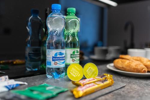 two bottles of water sitting on a table with snacks at Aparthotel New Lux in Wrocław