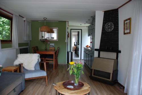 una sala de estar con un jarrón de flores sobre una mesa en Charmant chalet op een bospark op de Veluwe, en Putten