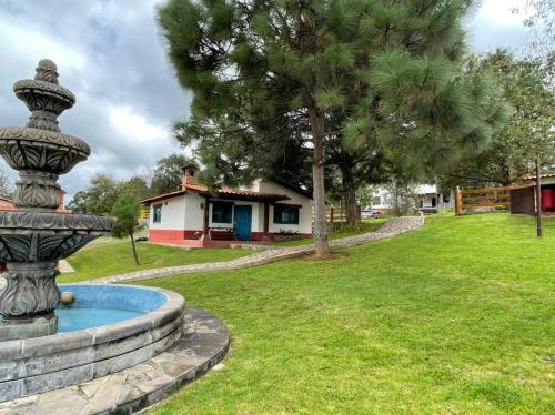 una fuente en un patio con una casa en el fondo en Cabañas Mazzatl 6 pax, en Mazamitla