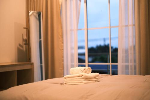 a pile of towels sitting on a bed with a window at Ma-TaÔ またお Café & hostel in Nan