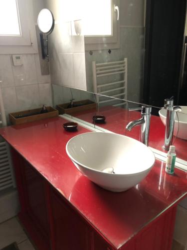 a bathroom with a white bowl sink on a red counter at CONDRIEU T3 Climatisé 2ème étage in Condrieu