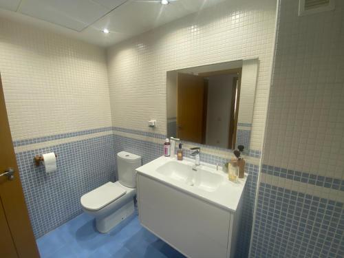 a bathroom with a sink and a toilet and a mirror at Playa Valencia Residencial Sol y Mar Terraza con Vistas y Parking in Playa Pobla de Farnals