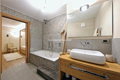 un baño con lavabo y bañera en Campiglio Luxury Apartment with SPA, en Madonna di Campiglio