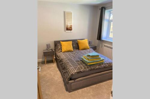 a bedroom with a bed with yellow pillows and a window at New apartment within short walk of the beach in Southbourne