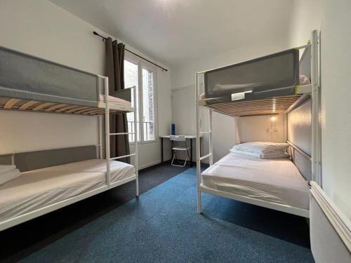2 łóżka piętrowe w pokoju z biurkiem w obiekcie Le Coffice Auberge de Jeunesse w Paryżu