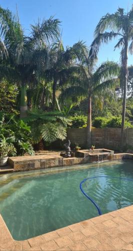 a swimming pool with a fountain and palm trees at eagles inn in Richards Bay