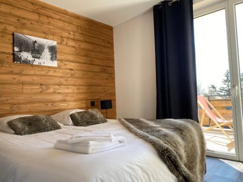 Résidence les 3 Sommets في Sarcenas: غرفة نوم بسرير مع جدار خشبي