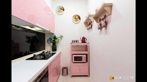 a pink kitchen with a stove and a microwave at Hua Ge B&B in Wujie