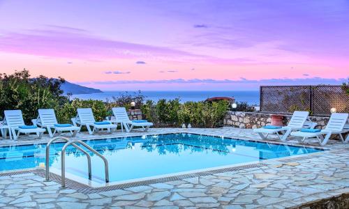 a swimming pool with white chairs and a poolvisorvisor at Mare Blue Villas Heated Pool in Kournás