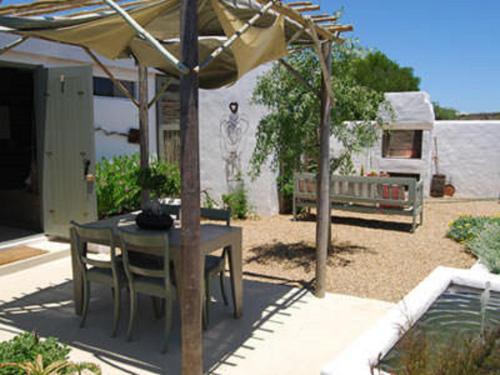 a table and chairs under an umbrella in a yard at Gelukkie in Paternoster