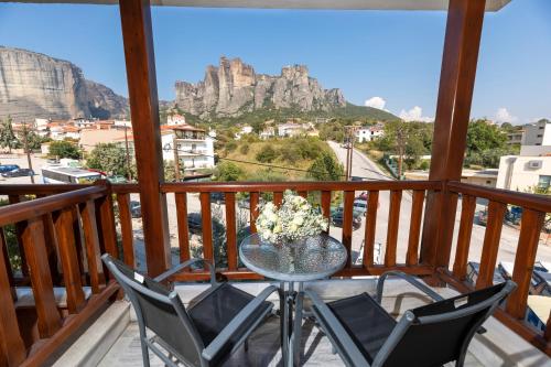 a table and chairs on a balcony with a view of cliffs at Famissi Hotel in Kalabaka