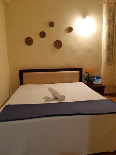 a white bed with a wooden headboard and a light at Palm Grove 1 Bhk Apartment at Candolim Beach with free Wifi in Candolim