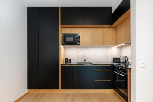 a kitchen with black cabinets and a microwave at TartuKodu Narva mnt 101a-1 in Tartu