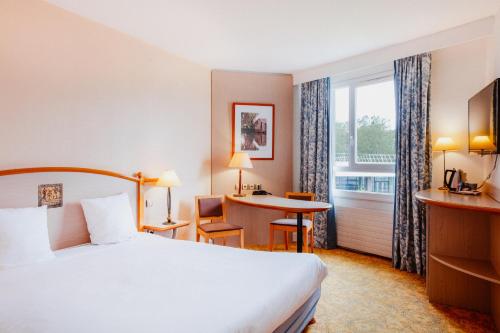 ヌヴェールにあるメルキュール ヌヴェール ポン ドゥ ロワールのベッド、デスク、窓が備わるホテルルームです。