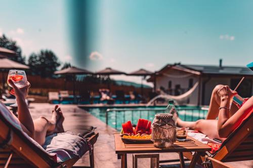 two people laying in chairs by a pool with drinks at Dakota forest retreat in Tsigov Chark
