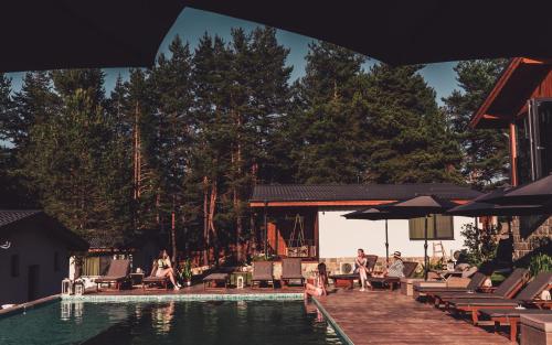 a pool with people sitting on chairs and umbrellas at Dakota forest retreat in Tsigov Chark