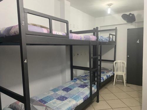 a room with three bunk beds and a chair at Ipanema Club Hostel in Rio de Janeiro