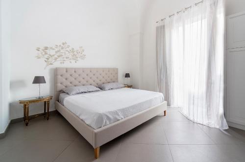 a white bedroom with a bed and a window at Piccola dimora Don Giovanni in Campi Salentina