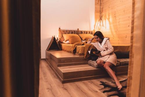 a woman sitting on a bed talking on a cell phone at Dakota forest retreat in Tsigov Chark
