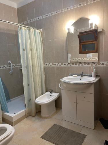 a bathroom with a sink and a toilet and a mirror at Fuseta Holiday House in Fuzeta
