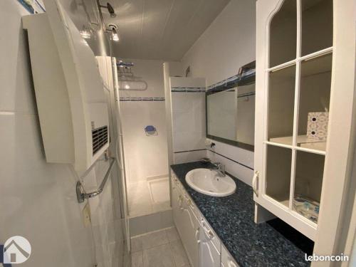 La salle de bains blanche est pourvue d'un lavabo et d'un comptoir. dans l'établissement Appt T2 tout confort face plage Argentière avec grande terrasse, à La Londe-les-Maures