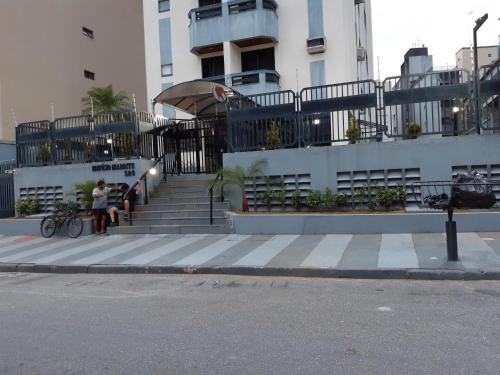 a woman standing next to a building with stairs at Apartamento Praia da Enseada in Guarujá