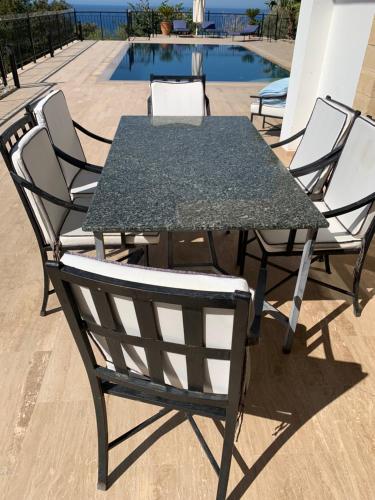 a table and chairs sitting next to a pool at Spectacular views from this villa in Lapta in Kérynia