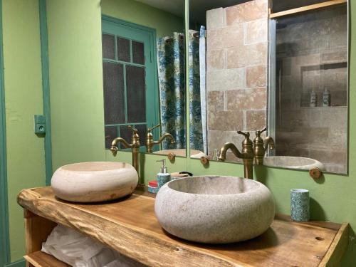deux lavabos sur un comptoir en bois dans une salle de bain dans l'établissement Demeure de charme à la campagne, à Laruscade