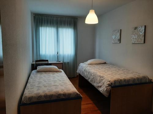 Habitación pequeña con 2 camas y ventana en Apartamento con jardin privado y piscina, en Cirueña