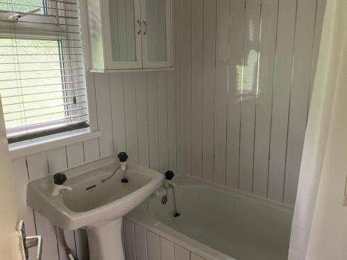 a white bathroom with a sink and a bath tub at Holiday Cabin Sleeps 5 Caernarfon Snowdonia in Caernarfon