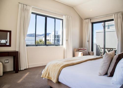 sypialnia z łóżkiem i dużym oknem w obiekcie Marine Square Luxury Suites w mieście Hermanus