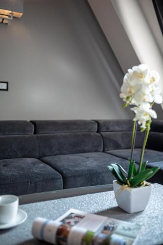 a living room with a couch and a vase with flowers on a table at Aparthotel New Lux in Wrocław
