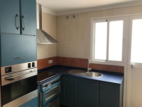 cocina con armarios azules, fregadero y fogones en Casa COMPARTIDA Algarrobo, en Algodonales