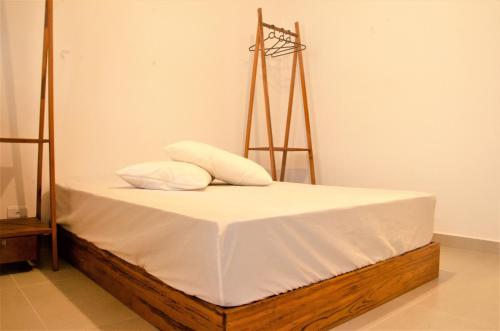 a bed with white sheets and two pillows on it at Vila Lorenzi & Apartamentos in Ubatuba