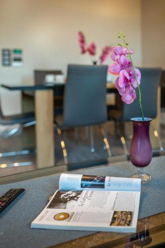 a table with a book and a vase with a flower at Aparthotel New Lux in Wrocław