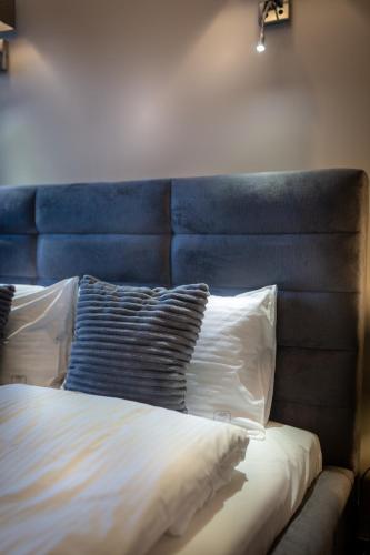 a bed with a blue headboard and two pillows at Aparthotel New Lux in Wrocław