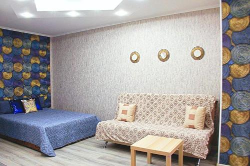 チュメニにあるApartment On 50let Oktyabrya 3/1のベッドルーム1室(ベッド1台、ソファ、テーブル付)