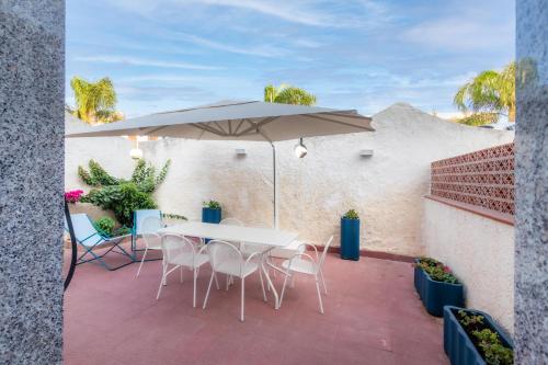 een patio met een tafel en stoelen en een parasol bij La Maiolica in Noto Marina