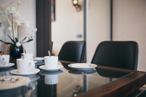 a table with chairs and cups and saucers on it at Aparthotel New Lux in Wrocław