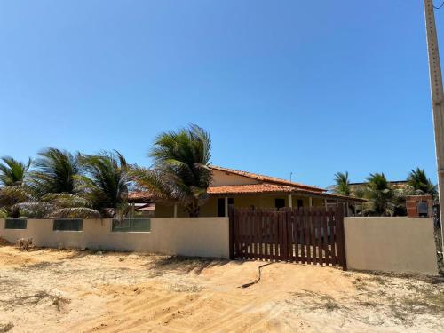 a house on the beach with a fence and palm trees at Casa na Praia in Luis Correia