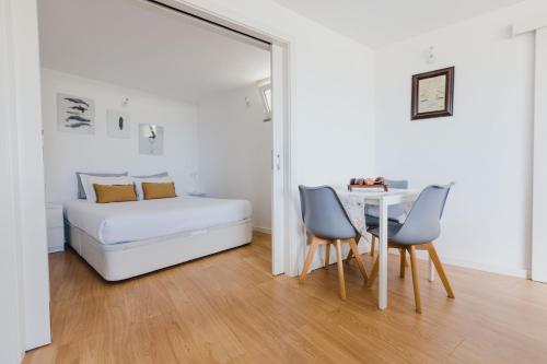 Un dormitorio con una cama y una mesa y sillas. en O Clube, en Porto da Cruz