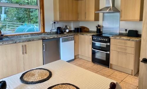 a kitchen with wooden cabinets and a stove top oven at Johnstonebridge Cottage in Johnstonebridge