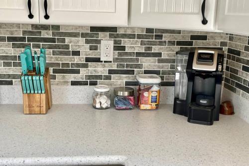 a kitchen counter with utensils and a coffee maker at Newly Renovated Carriage House Near Town & Beaches in Madison
