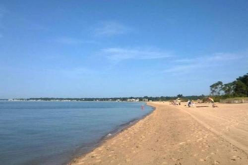 a beach with people on the sand and the water at Newly Renovated Carriage House Near Town & Beaches in Madison