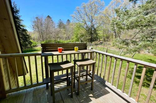 a porch with two chairs and a table on a deck at Newly Renovated Carriage House Near Town & Beaches in Madison
